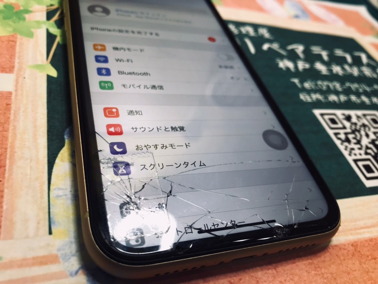 画面のガラスにひびが入っておりセロハンテープで補強されたiPhone XR